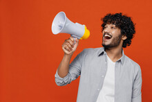 Jubilant Overjoyed Excited Vivid Young Bearded Indian Man 20s Years Old Wears Blue Shirt Hold Scream In Megaphone Announces Discounts Sale Hurry Up Isolated On Plain Orange Background Studio Portrait.