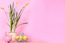 Eggs In An Iron Grocery Basket Daffodils In A Pot Watering Can Piggy Bank On A Pink Background. Savings At Easter, Discounts And Sales. Copyspase, A Place For Text