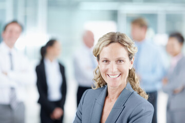 Wall Mural - Shes headed straight for the top. Positive mature businesswoman with her business team behind her - portrait.