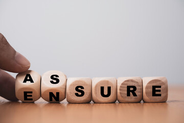 Fototapete - Hand flipping wooden cube block for change between Assure and Ensure for Insurance and assurance concept.