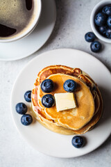 Canvas Print - Stack of blueberry pancakes with maple syrup and butter on white plate for breakfast.