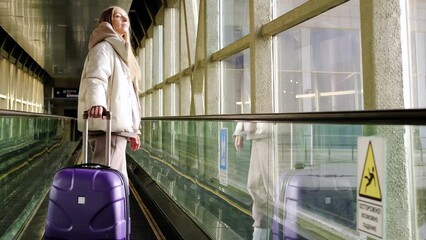 Wall Mural - woman in the moving walkway at the airport with a purple suitcase.