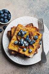 Canvas Print - French toast with blueberries, pecan and maple syrup for breakfast on white plate.