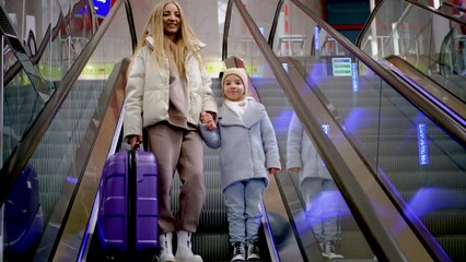 Wall Mural - Mother and daughter go down the escalator in the airport building