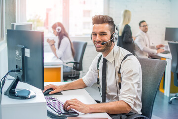 Wall Mural - Handsome male call center operator in headset working in modern office. Hotline support service concept