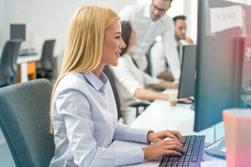 Side view portrait of beautiful business woman using computer at office.