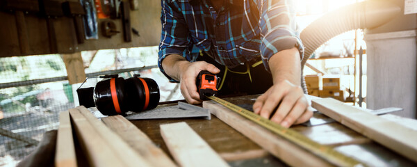 carpenter measure by a measure tape on the work bench. woodwork and furniture making concept in the 