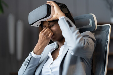 African american business woman suffer from eyes strain feel dizziness or headache after using virtual reality glasses for work in office. Woman suffers from eyes discomfort from vr headset goggles