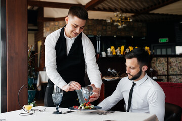 Wall Mural - The waiter makes an exquisite serving of seafood salad, tuna and black caviar in a beautiful serving on the table in the restaurant. Exquisite delicacies of haute cuisine close-up.