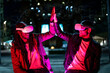 © MandriaPix - Young multiracial friends playing in virtual reality and win, people giving five to eac other with ar googles, neon light effect, nft transaction success