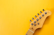 Closeup of electric guitar neck in solid yellow background with copy space