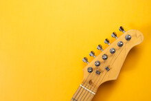 Closeup Of Electric Guitar Neck In Solid Yellow Background With Copy Space