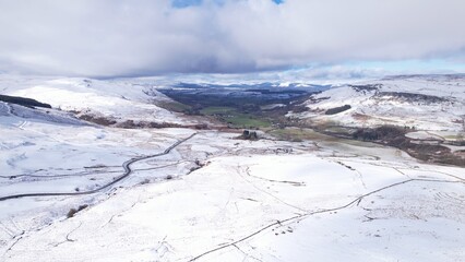 Wall Mural - A snow-covered Scottish landscape. Aerial image of a green, quiet, Scottish glen surrounded by snow-covered hills with snow-topped mountains in the distance. A cold, tranquil mood, scene.