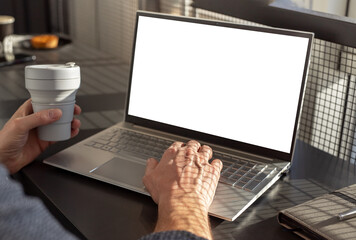 Poster - Man hands closeup typing on laptop mockup and holding takeaway collapsible eco cup. Businessman or student working or studying in cafe. City lifestyle concept. High quality photo