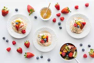 Homemade meringues topped with fresh fruit salad and honey.