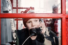Boy Talking On The Phone In A London Red Telephone Box