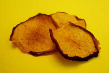 Wall Mural - three dried peach chips lie on a yellow background. healthy homemade food. peach