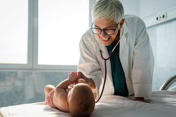 Wall Mural - Happy pediatrician doctor with baby checking possible heart defect