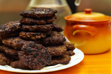 A mound of small beef liver pancakes on a plate next to a ceramic pot