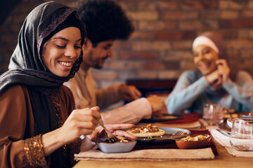 Wall Mural - Young happy Muslim woman enjoys in Ramadan meal with her friends.