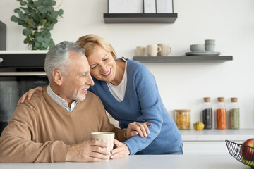 Senior wife snuggling up to husband while drinking tea