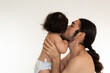 © Antonio Tanaka - portrait of a hispanic father and son kissing on the cheek on a white background