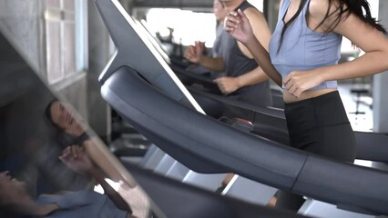 Wall Mural - Group of Healthy Asian athletic man and woman in sportswear jogging workout exercise on treadmill together at fitness gym. Wellness male and female do sport training on running machine at sport club