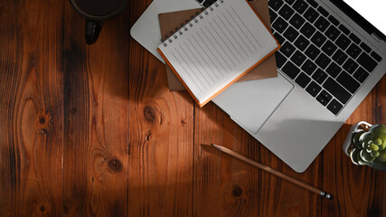 Top view notebook, laptop computer and succulent plant on wooden table.