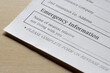 Closeup of the emergency contact information field on a patient information form isolated on a wooden background.