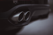 Double Oval Exhaust Tips On A Modern Sport Car Or SUV. Visible Two Tailpipes Coming Out From An Opening In The Rear Bumper. Black Color.