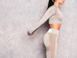 © halayalex - Fitness confident woman in sports clothing. Sexy young beautiful model with perfect body. Female posing near grey wall in studio. Stretching out before training. Unrecognisable