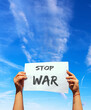 stop war sign raised by female hands on blue sky with white clouds