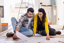 Smiling Woman Discussing Over Floor Plans With Boyfriend At New Home