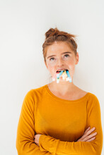 Woman Holding Toothbrushes In Mouth At Studio