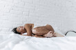 © Westend61 - Woman lying on bed in front of white wall at home