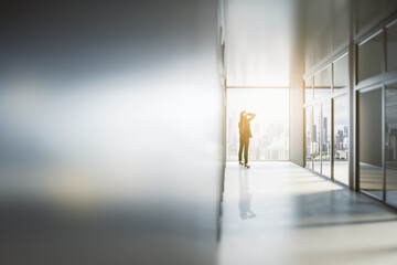 Poster - Businesswoman looking out of window in abstract bright light office interior with mock up place on silver wall. Success, future and tomorrow concept.