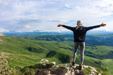 A girl on the background of the mountains and the Bermamyt plateau in Russia. June 2021