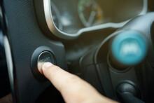 Driver pushing a vehicle engine start button, a modern car with keyless and go technology.