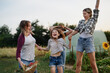canvas print picture - Happy little girl with mother and aunt jumping outdoors at community farm.