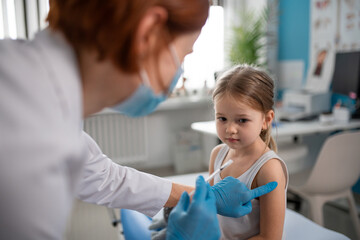 worried little girl getting vaccinated in doctor's office.