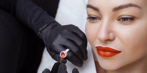 Wall Mural - Cosmetologist makes permanent makeup on a woman's face. Specialist applies a tattoo on the patient's lips close-up