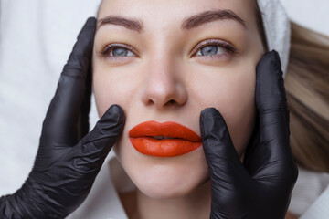 Wall Mural - Permanent makeup. Lip tattooing. Bright red sexy lips in the hands of a cosmetologist in black gloves