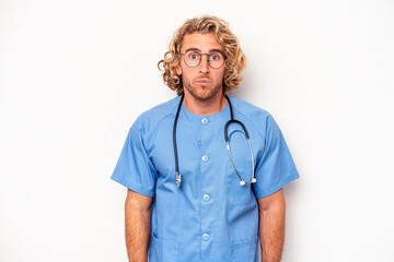 Wall Mural - Young nurse caucasian man isolated on white background shrugs shoulders and open eyes confused.