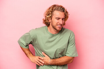 Young caucasian man isolated on pink background having a liver pain, stomach ache.