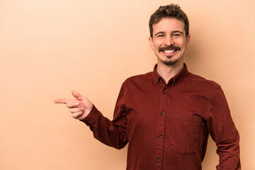 Wall Mural - Young caucasian man isolated on beige background smiling cheerfully pointing with forefinger away.