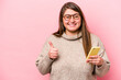 Young caucasian overweight woman holding a mobile phone isolated on pink background smiling and raising thumb up
