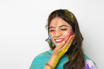 Wall Mural - Young indian smart girl with color powder in her hand and with face coloured with gulal for festival of colours Holi, a popular hindu festival celebrated across india, isolated over white background