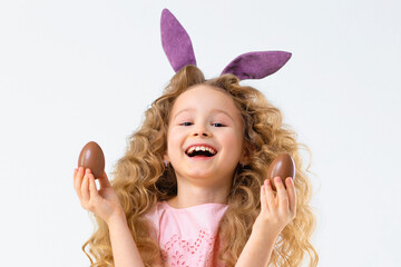 Happy holiday easter kids. Smiling cute little beautiful girl with rabbit hare bunny ears playing with chocolate eggs