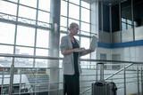 Fototapeta  - Woman looking at laptop standing near suitcase