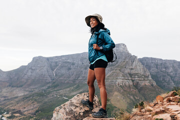 Young woman in sports clothes and hat enjoying the view during a hike